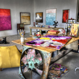 artist-studio-with-paintings-on-the-wall-and-painting-materials-on-top-of-the-table