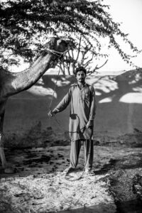 black-and-white-image-of-a-man-holding-a-camel-in-pakistan