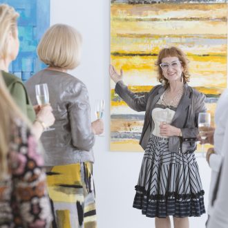 happy-elder-artist-presenting-her-painting-at-the-opening-private-dress
