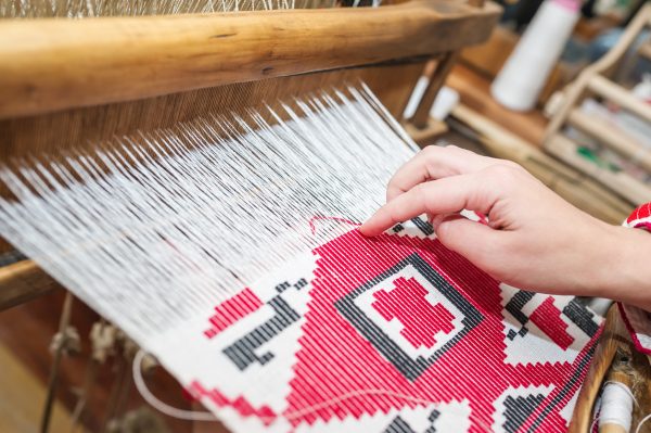 Close-up of tapestry loom with a hand weaving a pattern