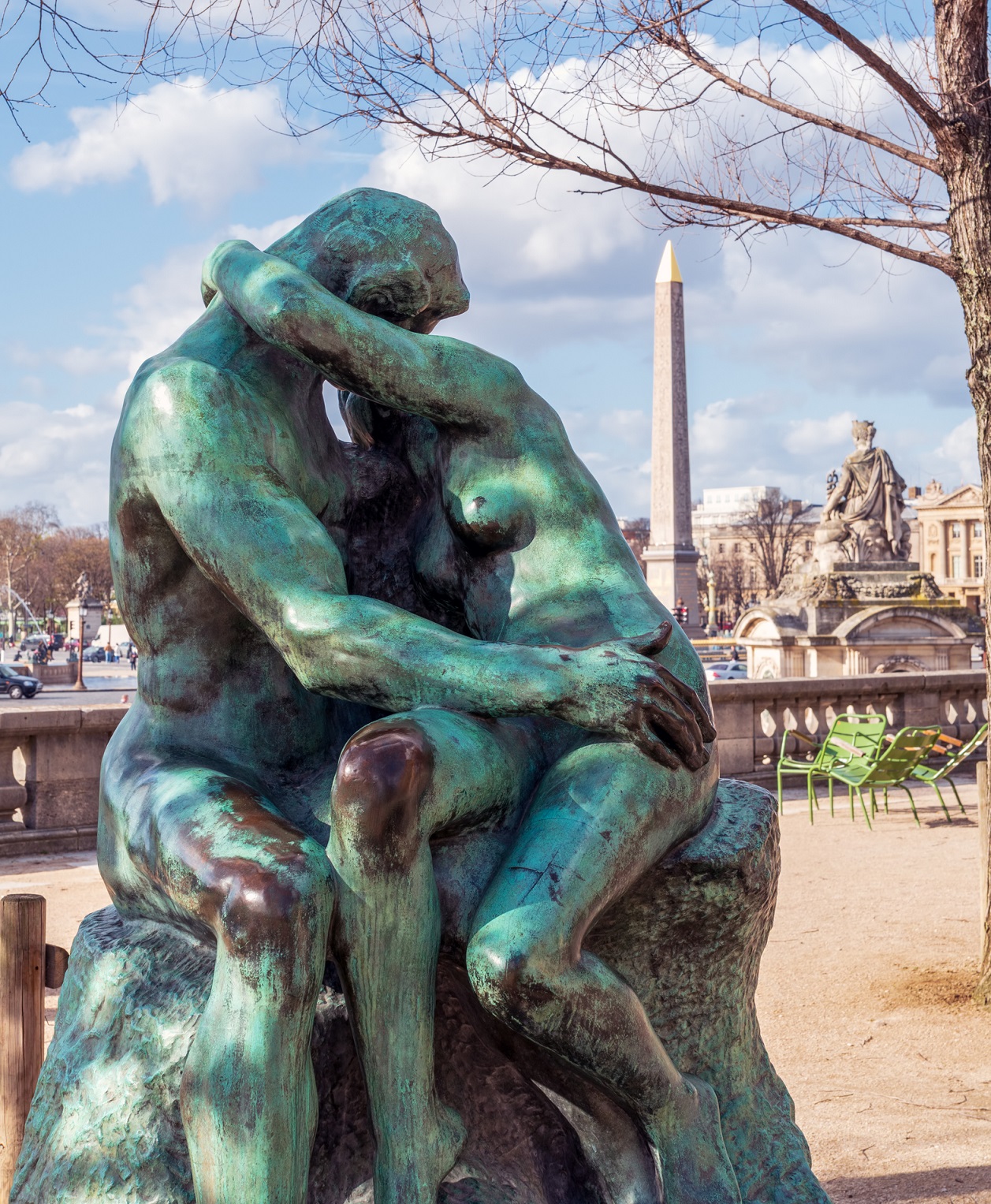 Bronze statue The Kiss by Auguste Rodin (1882) in the Tuileries Garden with Egyptian obelisk in background - Paris, France