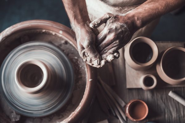 Top-view-of-potter-standing-near-pottery-wheel-and-holding-hands-together