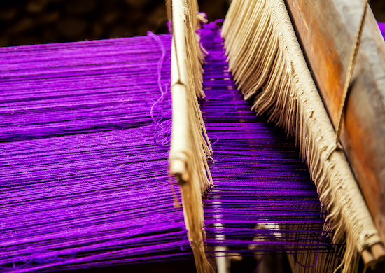 A traditional hand weaving loom with purple thread