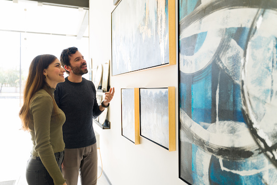 Man and woman in a bright gallery looking at artwork