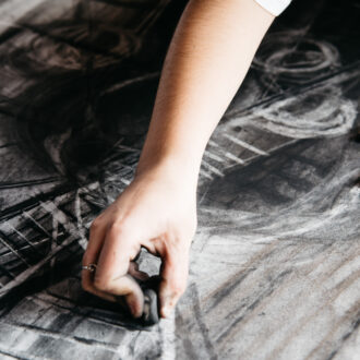 Young female artist painting with charcoal on paper