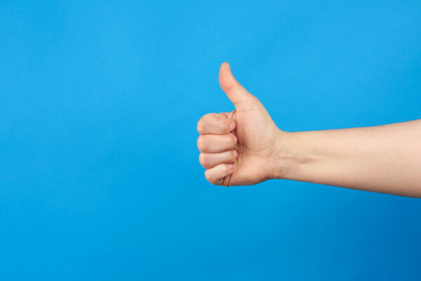Man's thumbs-up against a blue-background