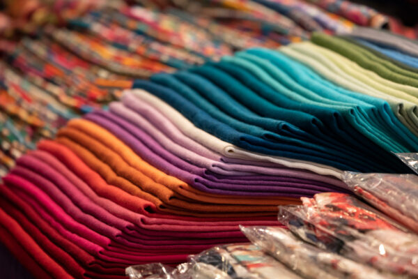 folded textiles grouped by color, creating a rainbow effect