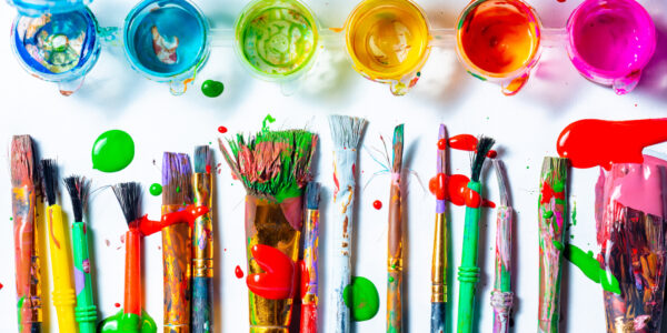 Row Of Messy Colorful Paint Brushes And Containers On White Background