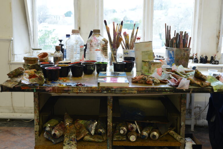 artist-studio-table with many art supplies covered in paint splatters
