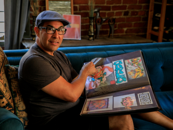 man sitting on couch flipping through an art portfolio