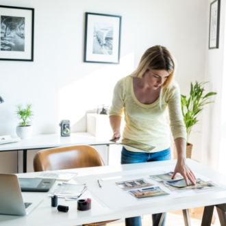 woman standing over a desk arranging photos in an art portfolio