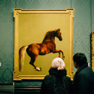 Art exhibition with visitors looking at a painting of a horse against a gold backdrop