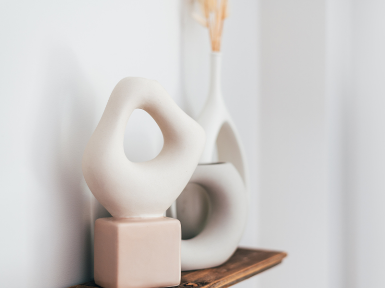 White modern ceramic sculptures displayed on a wooden shelf