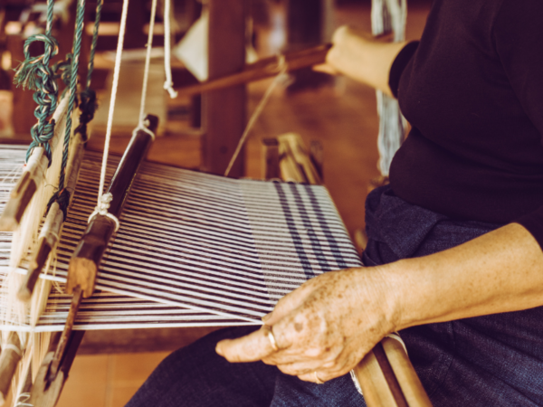 person working on a loom holding thread
