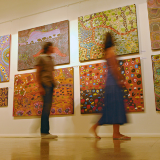 two people blurred out walking through an art exhibition