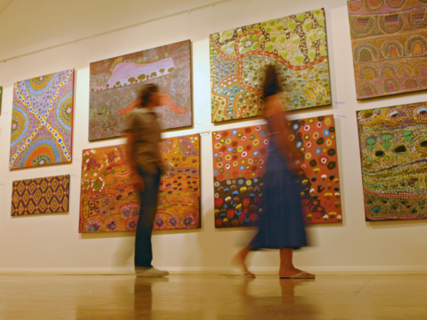 two people blurred out walking through an art exhibition