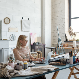 woman artist working on laptop in a bright white studio