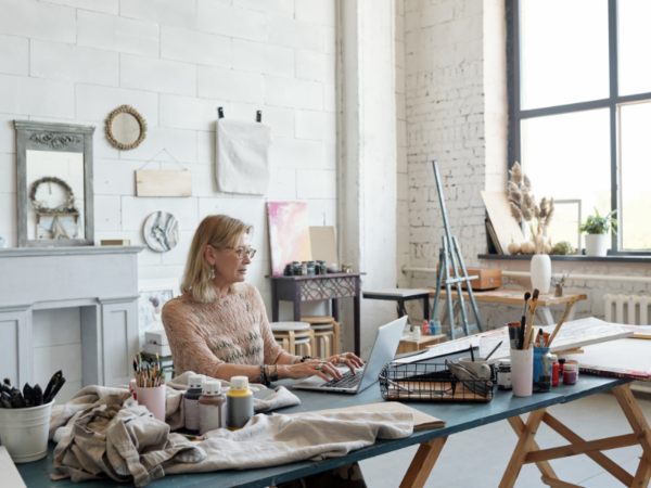 woman artist working on laptop in a bright white studio