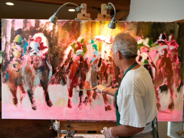 Older artist painting on a large canvas in studio